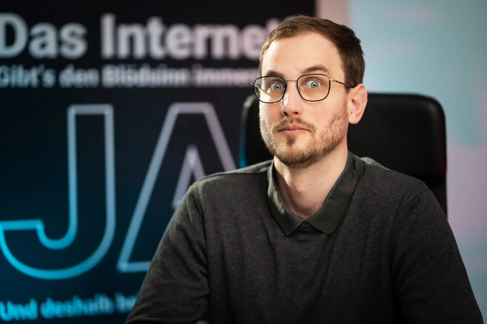 Joshua Stark von STARK Marketing vor einem Display mit der Aufschrift „Das Internet? Gibt's den Blödsinn immer noch? JA“